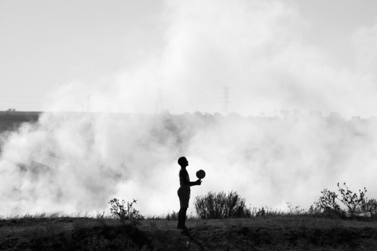 Child playing with ball near veld fire. Phola, Mpumalanga